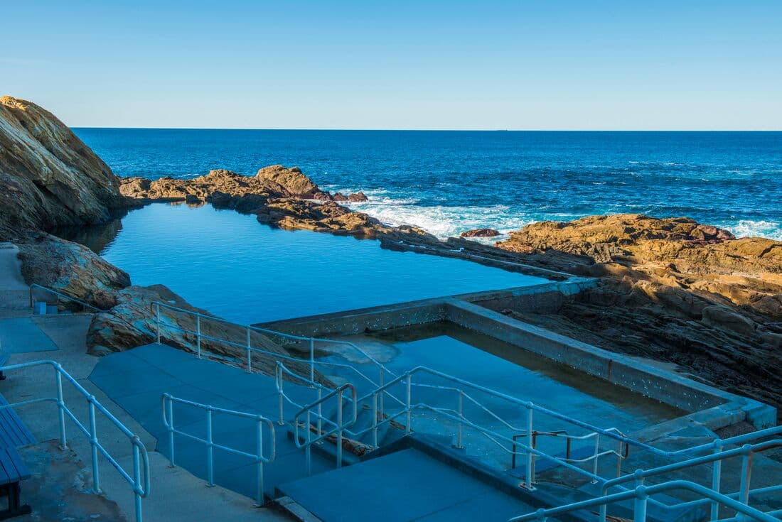 Bermagui Blue Hole swimming pool with view of the horizon where the sea meets the sky in New South Wales, Australia