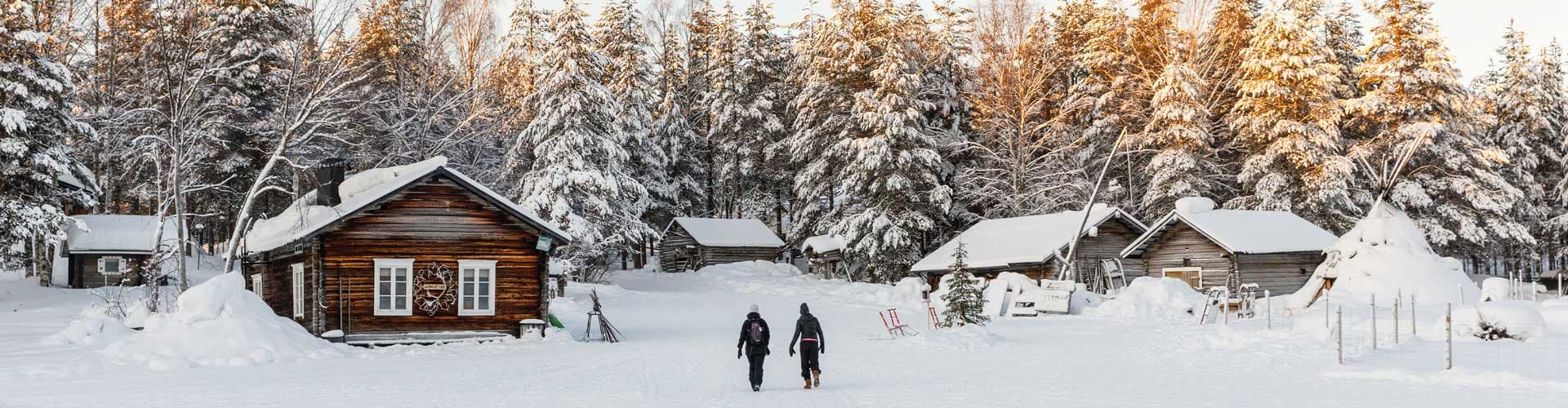Two travellers walk through thick snow to get to cabin in Finland