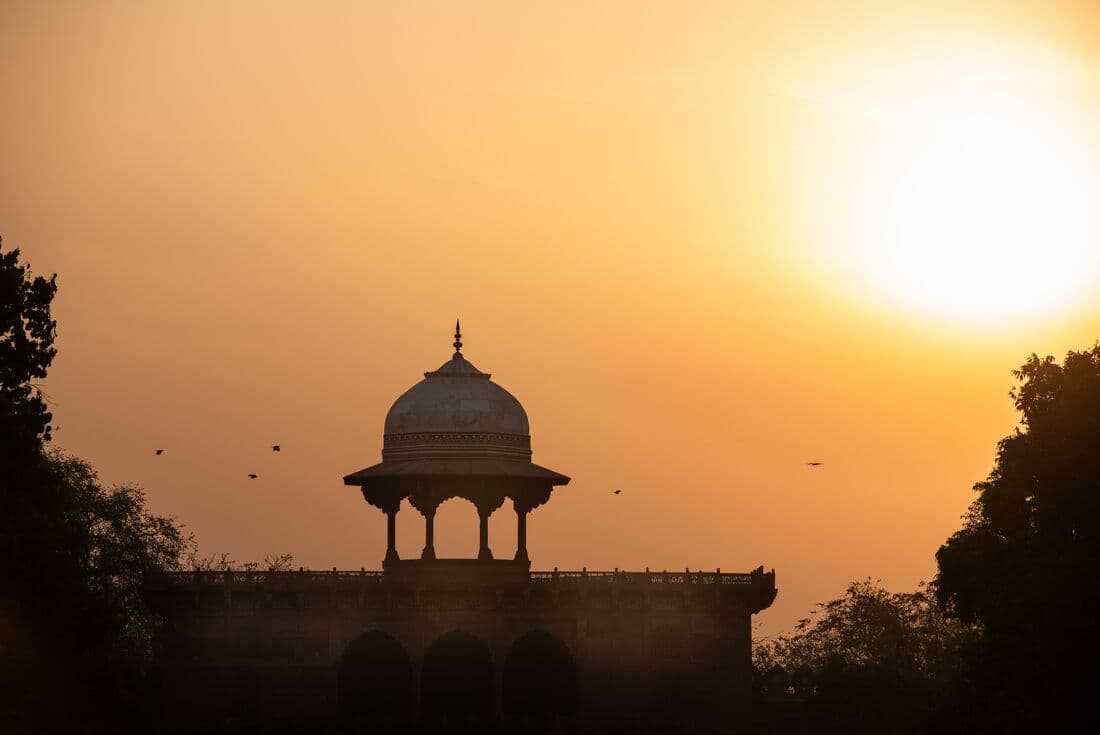 A warm sunrise behind the Taj Mahal, creating silhouettes of birds flying by, Agra, India