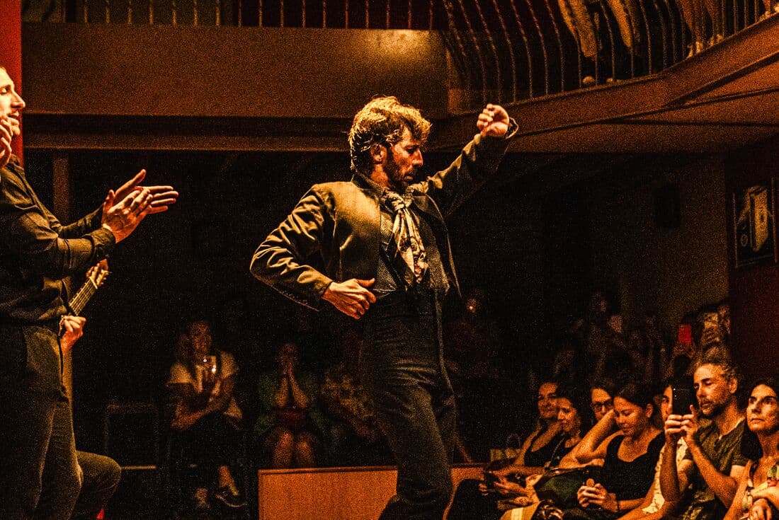A flamenco dancer performs on stage backed by a band in the Casa de la Memoria while travellers watch