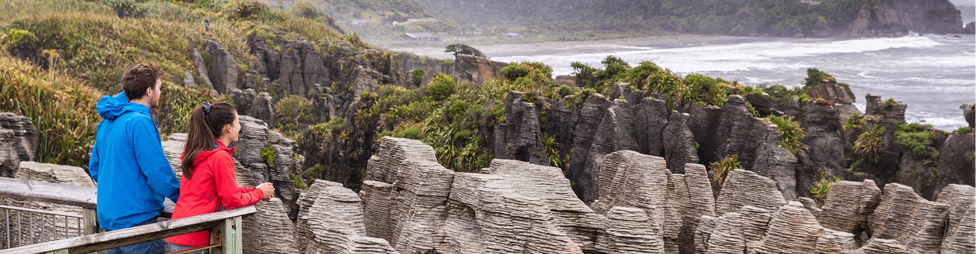 Couple admiring Punakaiki Pancake Rocks from viewpoint, South Island, New Zealand