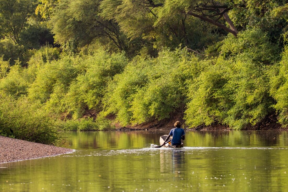 A fisherman rows a dugout canoe pirogue up the Gambia River