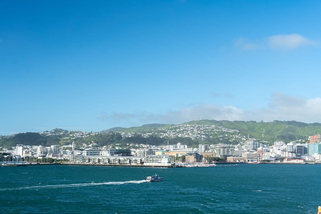 A scenic view of a  ferry in Wellington Harbour and the city and mountains in the background, New Zealand