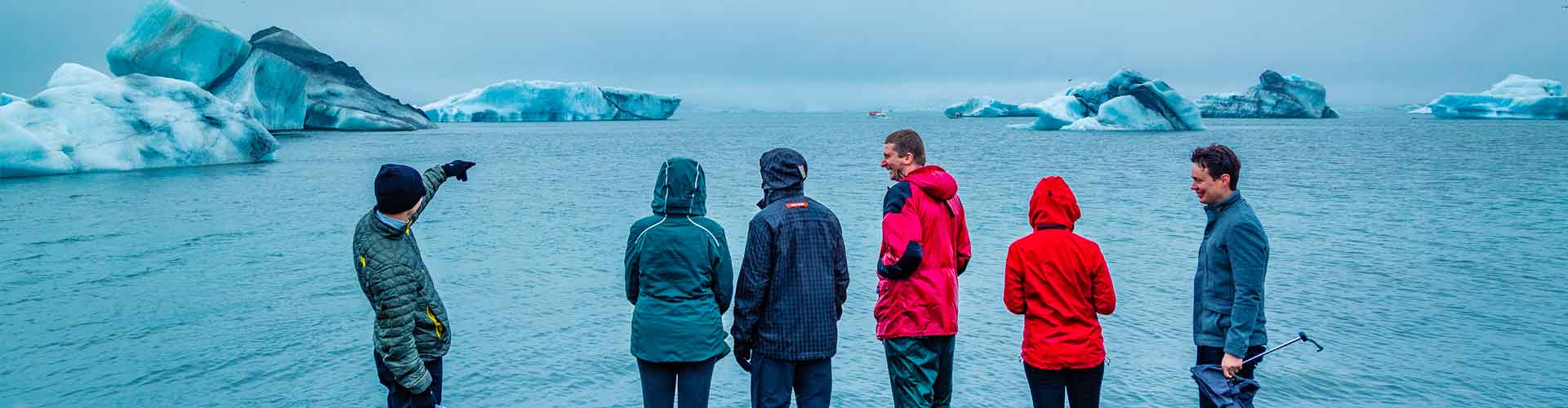 Group of travellers look at Jokulsarlon Glacier from the coastline