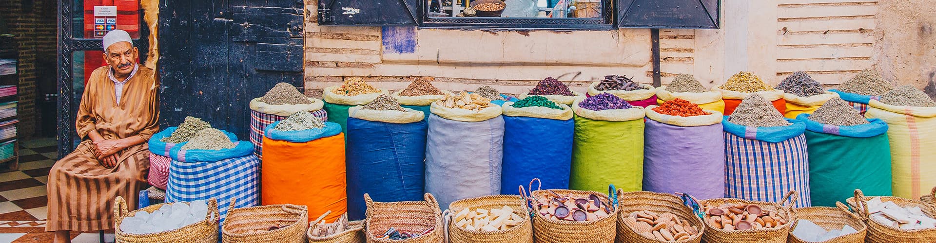 Local man sits at colouful spice market, Marrakech, Morocco