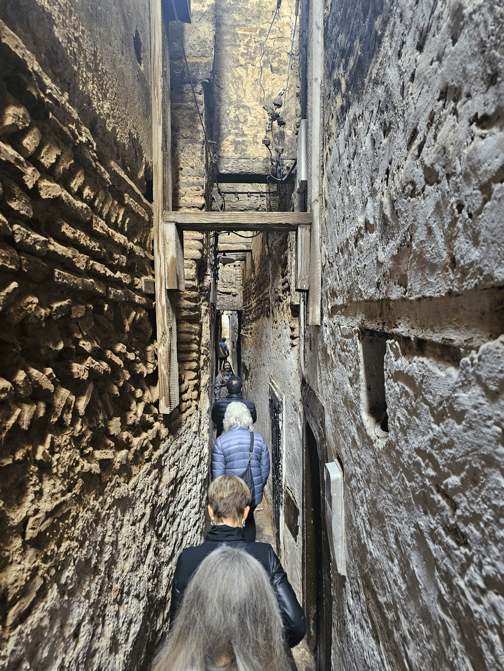 Travellers following a narrow stone lane through the Fes medina.