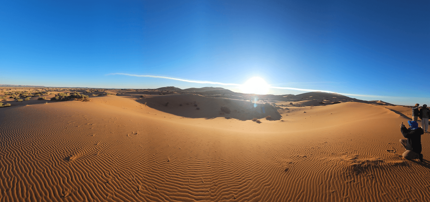 Low sun over rippled sand and dunes near Merzouga.